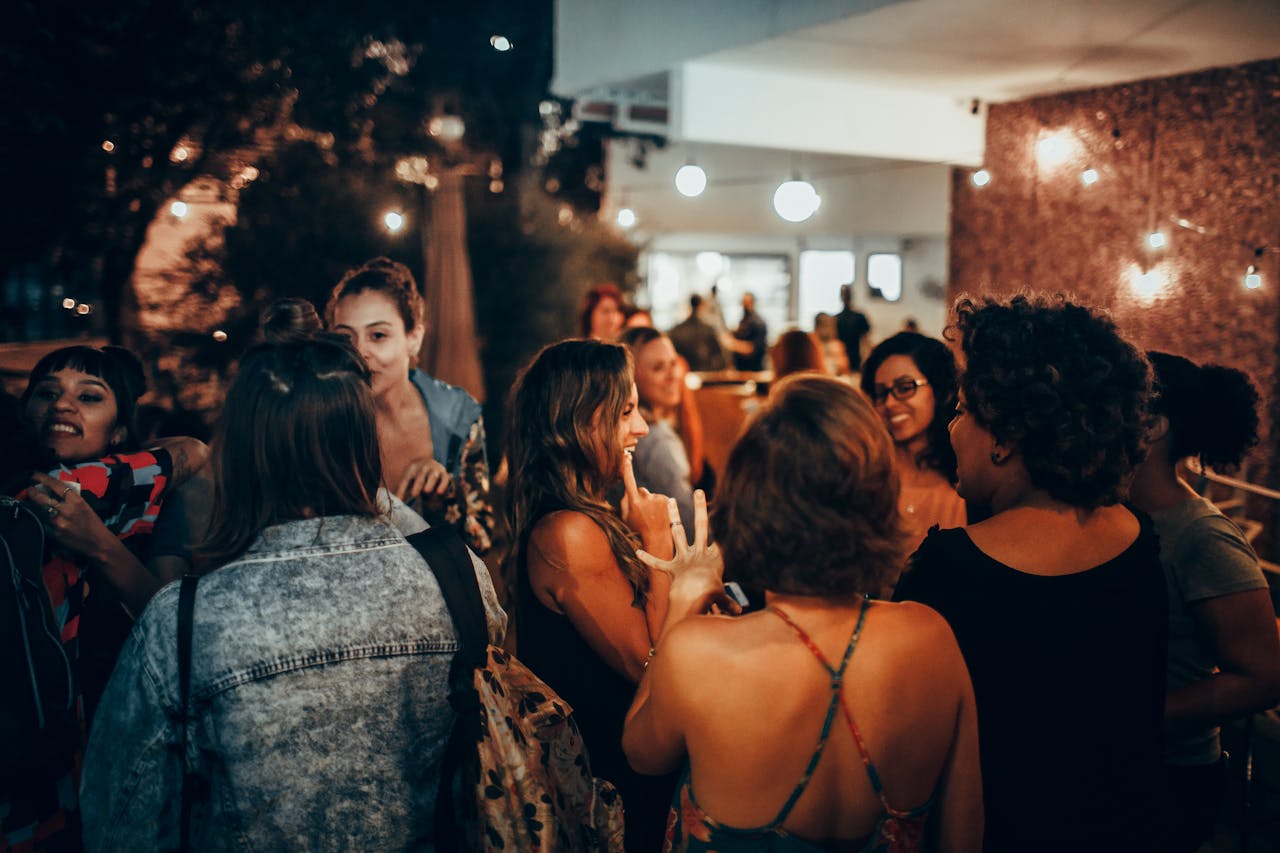 A vibrant group of adults socializing outdoors at night, creating a warm and lively atmosphere.