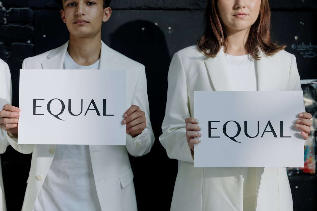 Young individuals holding Equal signs promoting equality indoors.