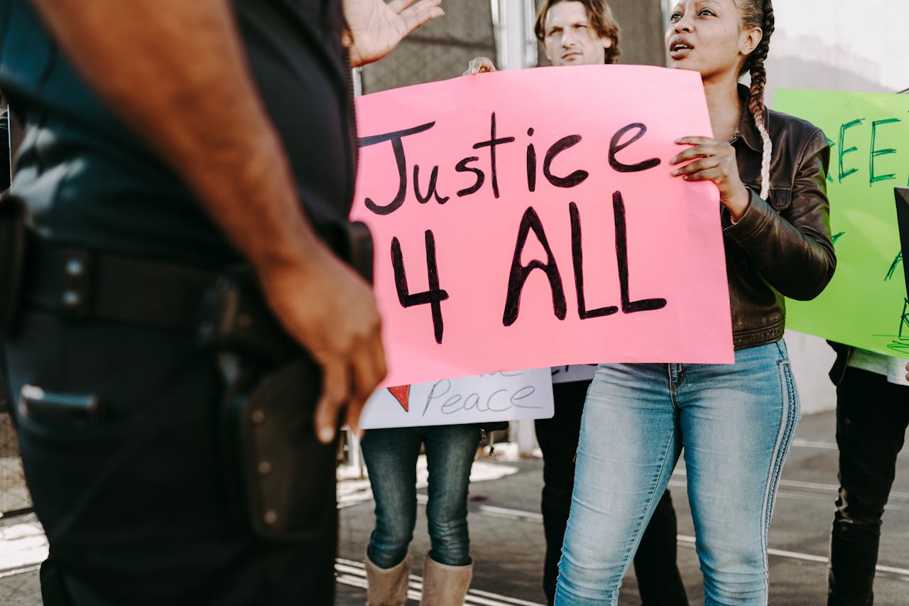 A group of diverse adults protesting for justice with vibrant signs outdoors.